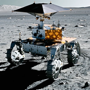 A Large Robotic Vehicle, Possibly A Rover, Driving Across A Rocky Terrain
