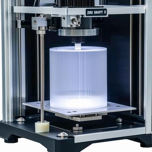 A Machine Is Holding A Clear Plastic Object, Which Appears To Be A Glass Or A Plastic Container