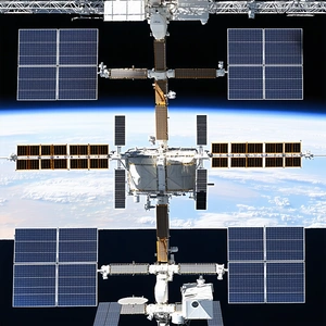 A Large Space Station Is Shown In The Image, With A Smaller Space Station Docked To It