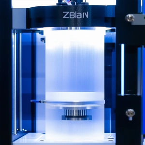 A Large, White, And Blue 3d Printer, Which Is In The Process Of Printing A Plastic Object