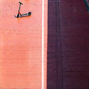 Urban Aerial Photography: (city:1.15) Electric Scooter In Quiet Side Street With Small, Black,