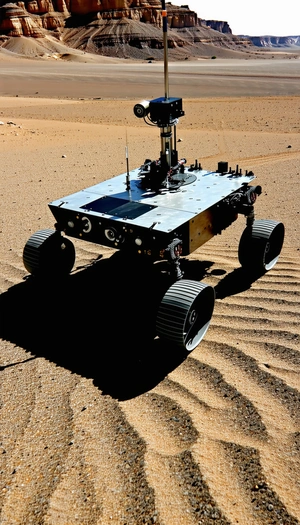 A Robotic Vehicle, Possibly A Rover, Sitting On A Sandy Surface
