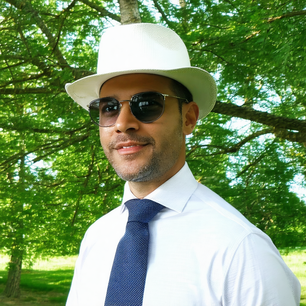 Man wearing a white hat and sunglasses, standing in a gra...