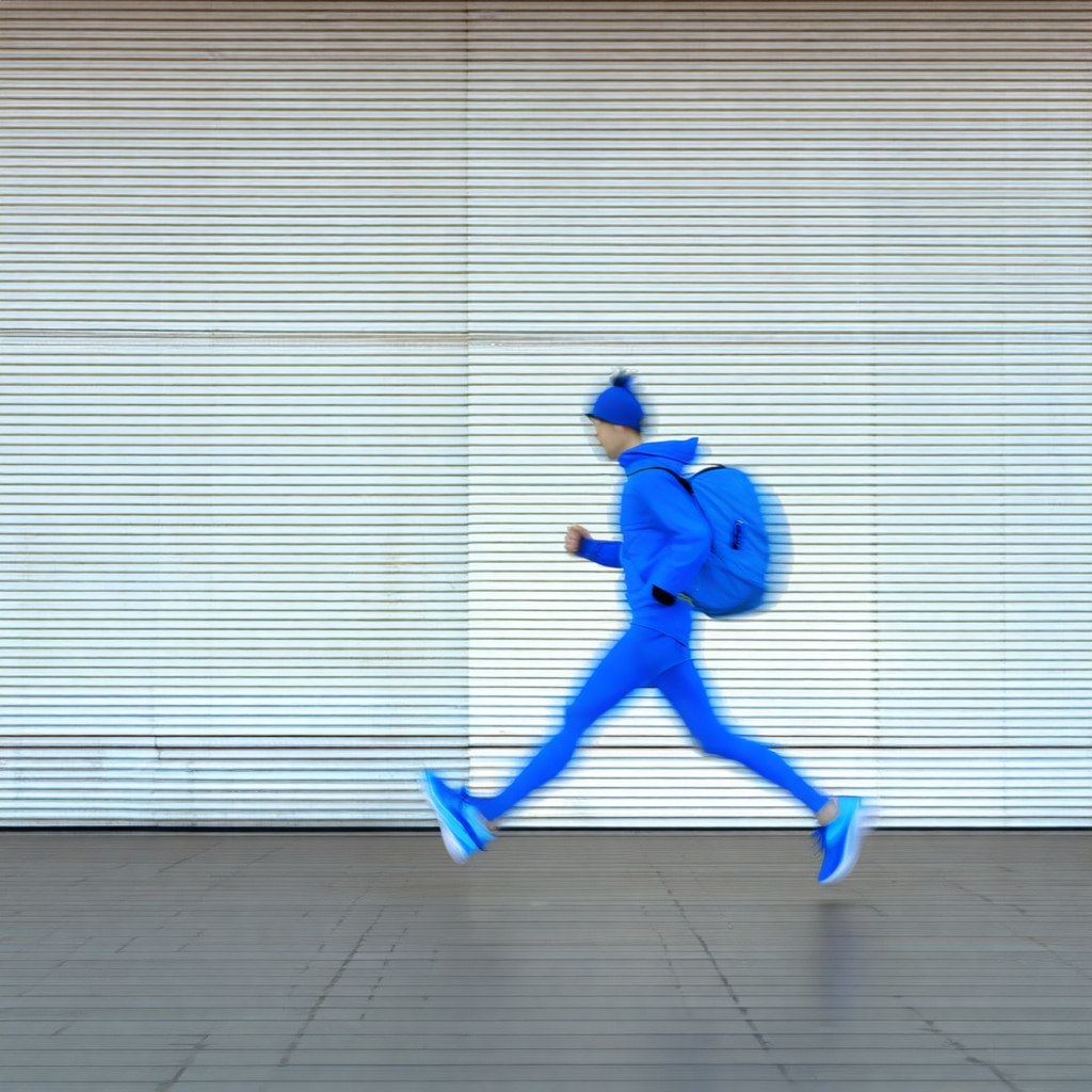 Man wearing a blue jacket and a blue hat, running down a ...